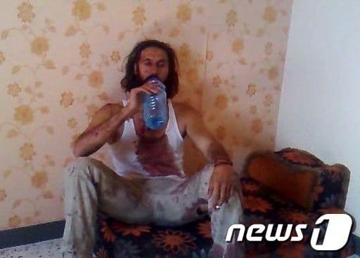 본문 이미지 - 생포 이후 숨지기 직전의 카다피 아들 무타심의 모습. 담배를 피우며 물을 마시고 있다. AFP © News1