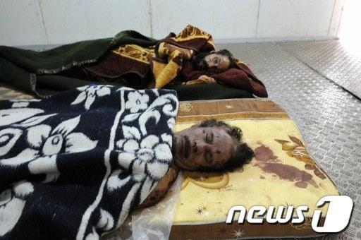 본문 이미지 - 리비아 미스라타 야채 시장 냉동 창고 바닥에 놓여있는 카다피(앞)와 4남 무타심의 시신 © AFP=News1 