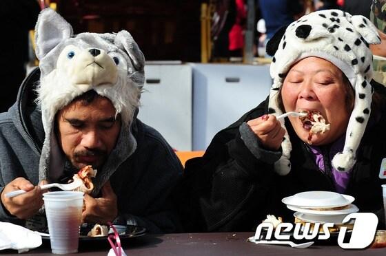 본문 이미지 - 인형 모자를 쓴 노숙자 2명이 지난해 추수감사절 연휴동안 미국 봉사센터인 로스앤젤레스 미션에서 무료 식사를 하고 있다. © AFP=News1 