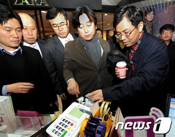 본문 이미지 - 12월3일 명동 NFC존을 방문한 차이나모바일 경영진이 SK플래닛 이주식 서비스 플랫폼 BU장(오른쪽 두번째)에게 NFC 서비스에 대한 설명을 들으며 체험해보고 있다. © News1 