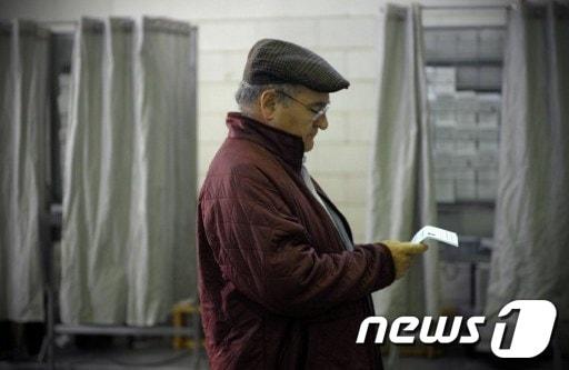 본문 이미지 - 21일(현지시간) 스페인 북부 갈리시아의 비고시(市)에 위치한 투표소에서 한 남성이 투표 용지를 쳐다 보고 있다. © AFP=News1