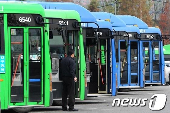 본문 이미지 - 택시를 대중교통 수단에 포함시키는 내용의 법률 개정안이 국회 법사위를 통과해 버스업계 전면 파업 위기를 맞은 21일 오후 서울 시내 한 공영차고지에 주차된 노선버스들 앞에서 한 버스기사가 서 있다. 전국버스운송사업조합연합회는 앞서 법률개정안이 국회 법사위를 통과할 경우 오는 22일 0시부터 버스 운행 무기한 중단을 예고했다. 2012.11.21/뉴스1 © News1 한재호 기자