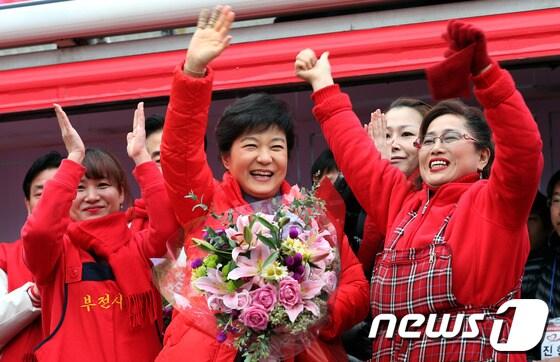 본문 이미지 - 박근혜 새누리당 대선후보가 30일 오후 부산광역시 진구 부전시장 앞에서 유세를 마친 뒤 시장 상인회에서 전달한 꽃다발을 들고 환하게 웃으며 손을 흔들고 있다. 2012.11.30/뉴스1 © News1 박정호 기자