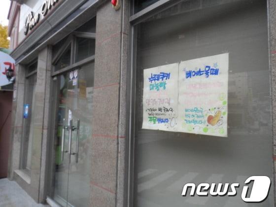 본문 이미지 - 27일 생활고를 비관해 주인이 자살한 동네빵집. 오래전 붙인 것으로 보이는 홍보문구와 함께 문이 굳게 닫혀져 있다. © News1 