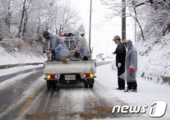 본문 이미지 - 28일 내린 폭설로 가지산으로 이어지는 도로 등이 교통통제된 가운데 밀양시 제설작업반이 모래를 뿌리고 있다. <밀양시 제공>© News1 