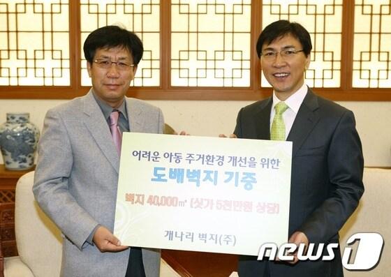 본문 이미지 - 송의섭회장이 14일 안희정도지사에게 벽지 기증서를 전달하고 있다© News1 