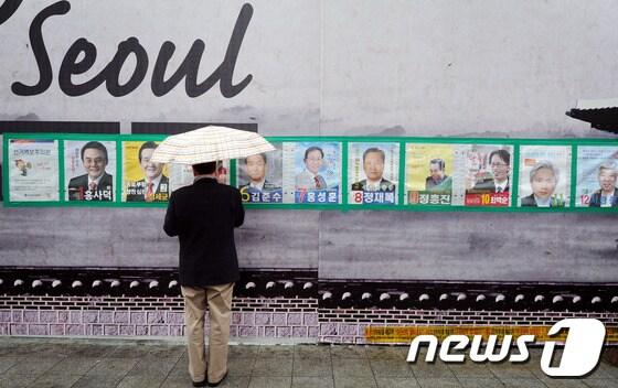 본문 이미지 - 4·11총선을 하루 앞둔 10일 오후 서울 종로구 한 거리에서 한 시민이 종로구에 출마한 후보들의 벽보를 지켜보고 있다. 2012.4.10/뉴스1 © News1   이동근 인턴기자