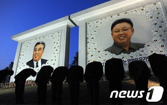 본문 이미지 - 김일성(오른쪽)과 김정일 초상화에 경배하는 북한 주민들.© AFP=News1 
