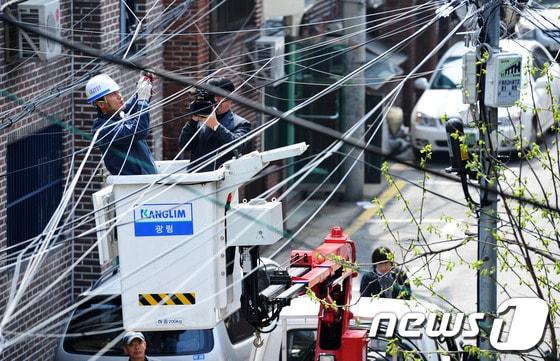 본문 이미지 - 인터넷과 케이블TV의 급속한 증가는 생활의 편리를 가져왔지만 거미줄처럼 뒤엉킨 각종 '선'들은 푸른 하늘을 가리는 도심 속 흉물이 된 지 오래다. ⓒ 뉴스1 DB