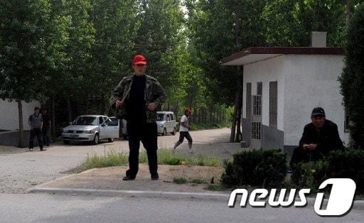 본문 이미지 - 중국 시각장애 인권변호사 천광청이 가택연금 도중 탈출한 산동성 이난현 동스구 마을 앞에서 사복경찰들이 경비를 서고 있다. © AFP=News1  