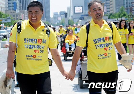 본문 이미지 - 지난 2012년 발달장애인법 제정과 국민기초생활보장법 개정을 촉구하며 광주에서 서울까지 500KM 도보행진에 나선 이진섭-이균도(왼쪽) 부자의 모습   2012.5.21/뉴스1