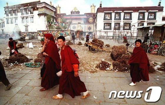 본문 이미지 - 조캉 사원 앞을 지나가고 있는 티베트 불교 승려들(자료사진).© AFP=News1 