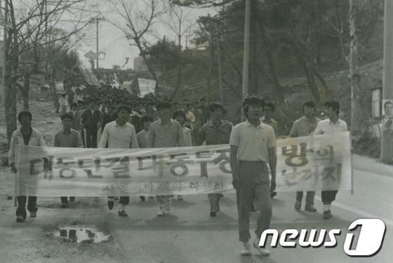본문 이미지 - 1987년 6월항쟁 당시 울산대학교 학생들이 학교 정문 부근에서 가두시위를 벌이고 있다. 맨 앞에 서서 무리를 이끌고 있는 학생이 지금의 울산중구의회 부의장인 신성봉 의원이다. / 사진제공=신성봉 울산중구의원 © News1 