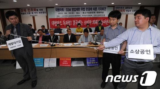 본문 이미지 - 전국소상공인단체연합회 회원 및 관계자들이 지난 25일 서울 여의도 중소기업중앙회에서 열린 대형마트·SSM 영업제한 위법 판결에 따른 기자회견에서 대기업과 소상공인의 관계를 밧줄을 이용해 퍼포먼스를 벌이고 있다. 2012.6.25/뉴스1 © News1 양동욱 기자