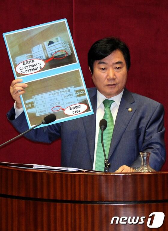 본문 이미지 - 이석현 민주통합당 의원이 18일 오전 서울 여의도 국회 본회의장에서 열린 정치에 대한 대정부질문에서 권재진 법무부장관에게 장진수 전 총리실 공직윤리지원관실 주무관의 휴대폰에서 복구된 류충렬 전 공직복부관리관에게서 받았다는 관봉 형태의 5,000만원 사진을 들고 민간인 사찰관련 질의를 하고 있다. 2012.7.18/뉴스1 © News1 박정호 기자