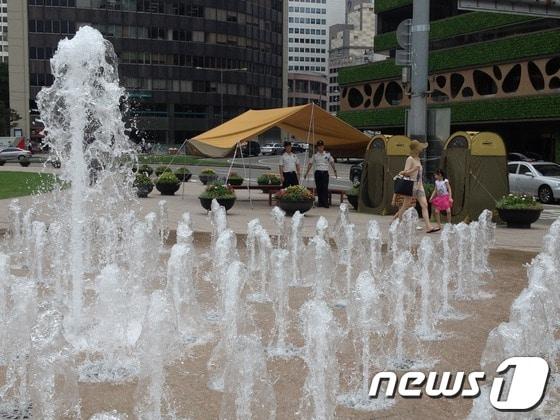 본문 이미지 - 서울시는 물놀이하는 어린이들을 위해 서울광장 분수대 주변에 이동식 탈의실과 임시 그늘막을 설치했다. © News1 박태정기자  