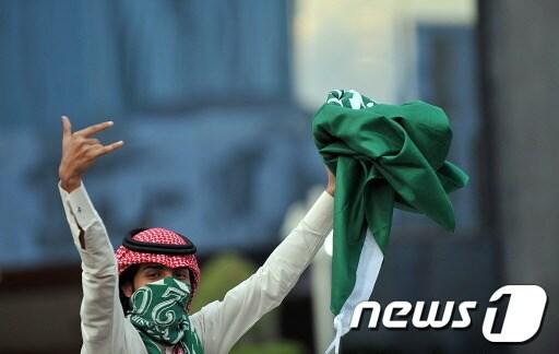 본문 이미지 - 한 사우디아라비아 여성이 국가기념일을 맞이해 국기를 들고 환호하고 있다. (기사 내용과 관련 없음) ©AFP=News1 