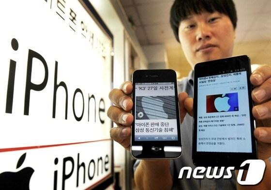 본문 이미지 - 법원이 삼성과 애플의 특허권 침해에 대한 첫 소송에서 사실상 삼성의 손을 들어준 24일 오후 서울 용산구의 한 통신기기 매장에서 직원이 삼성 갤럭시S2 제품과 애플 아이폰4 제품을 들어 보이고 있다. © News1 이정선 기자