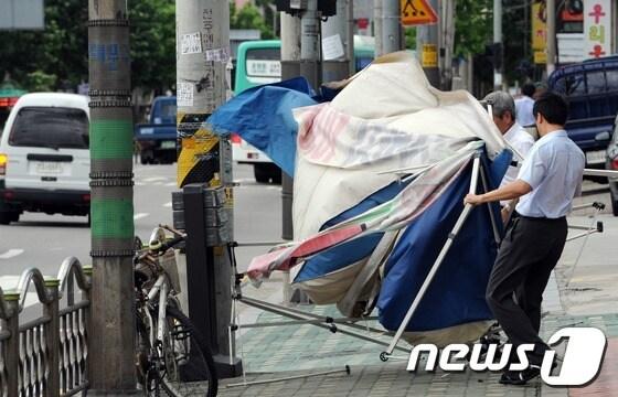 본문 이미지 - 초강력 태풍 '볼라벤(BOLAVEN)' 영향으로 전국 곳곳에서 피해가 발생하고 있는 28일 오후 서울 동대문구 떡전사거리 인근 인도에서 상가 관계자들이 강풍에 날린 천막을 치우고 있다. © News1 허경 기자
