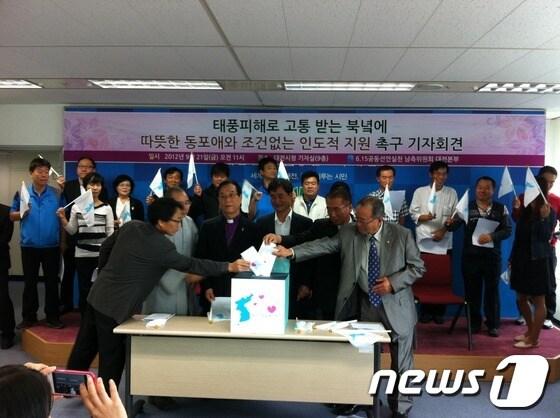 본문 이미지 - 6·15공동선언실천 대전본부가 21일 대전시청 브리핑실에서 조건 없는 대북 수해복구 지원을 촉구하는 기자회견을 열고, 다음 달 중순까지 밀가루 30t(1500만 원 상당)을 목표로 수해지원 모금을 진행한다고 밝혔다. 대전본부 관계자들이 한반도가 표시된 모금함에 각자 모금액을 넣고 있다. © News1 