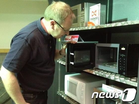 본문 이미지 - 영국의 소비자정보지 '위치'로부터 '베스트 바이' 제품으로 선정된 대우일렉의 전자레인지를 현지 외국인이 살펴보고 있다.(사진=대우일렉)© News1  