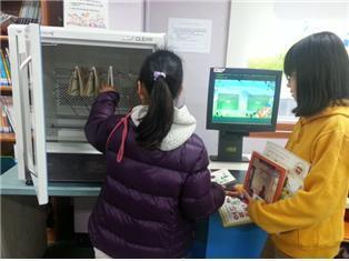 본문 이미지 - 한 아이가 서울 도봉도서관에 설치된 책소독기를 이용하고 있다. (서울시교육청 제공) © News1 