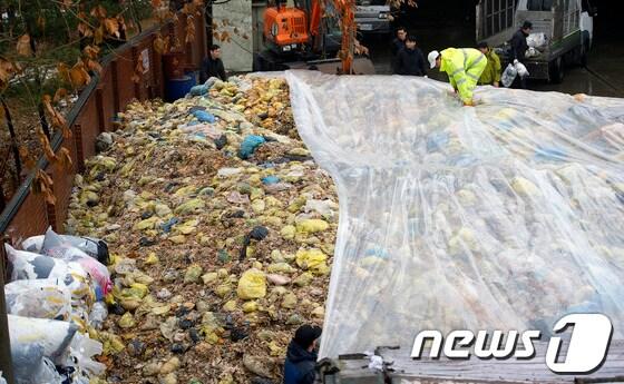 본문 이미지 -  21일 서울 관악구 음식물쓰레기 중간 집하장에서 비를 막기 위해 비닐로 쓰레기를 덮고 있다. 2013.1.21/뉴스1 © News1 이명근 기자