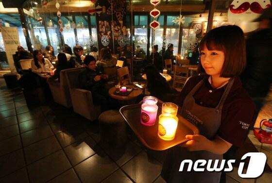본문 이미지 -  23일 저녁 서울 노원구 상계동 와우 쇼핑몰 탐앤탐스 커피숍이 '사랑의 불끄기 카페'에 동참해 일부 조명을 소등하고 촛불을 켠채 운영되고 있다. 서울시는 ‘사랑의 불끄기 카페’를 커피전문점과 제과점 중 에너지 절약 자율목표를 정하고 이를 실천하고 있는 가게를 중심으로 조성할 계획이다. © News1 송원영 기자  