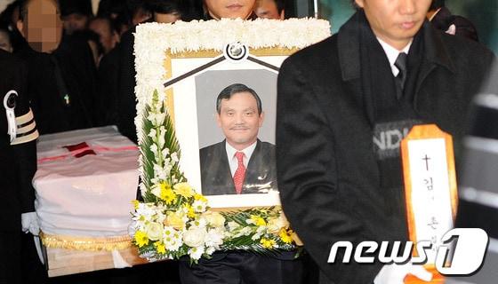 본문 이미지 - 1970~80년대 국내 주먹계를 휩쓸었던 조직 ‘범서방파’의 두목 김태촌 씨의 발인식이 열린 8일 오전 서울 송파구 서울아산병원에서 고인의 영정을 앞세운 운구행렬이 운구차로 옮겨지고 있다.  2013.1.8/뉴스1 ⓒ News1