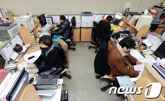 본문 이미지 - 고용노동부 소속 공무원들이 무릎담요를 덮고 외투를 입은 채 업무를 보고 있다.