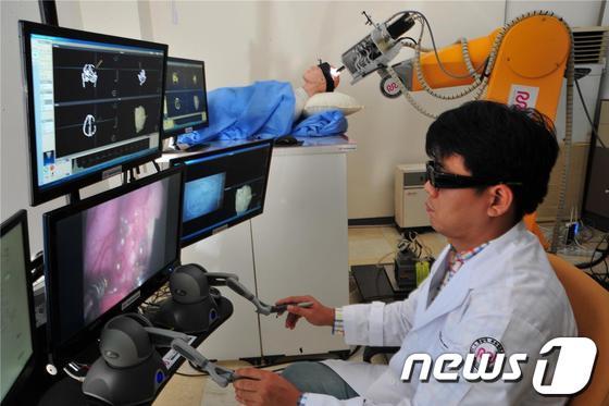 본문 이미지 - 전남대 로봇연구소에서 개발한 뇌수술로봇을 연구원이 시연하고 있다. 이 로봇은 현재 시제품 개발을 끝내고 임상용 제품 개발에 들어갔다/사진제공=전남대© News1 