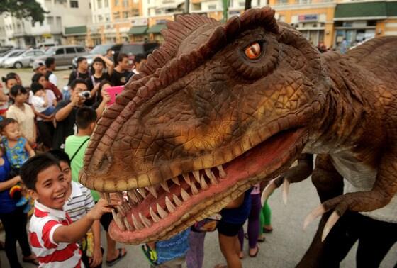 본문 이미지 - 30일(현지시간) 필리핀 마닐라에서  할로윈 의상 퍼레이드가 열린 가운데 한 소년이 공룡 마스코트를 만져보고 있다. 이  행사는 여러가지 다른 무서운 분장 공개를 통해 창의적이고 재미있는 방법으로 할로윈을 기념하기 위한 것이다. © AFP=뉴스1  