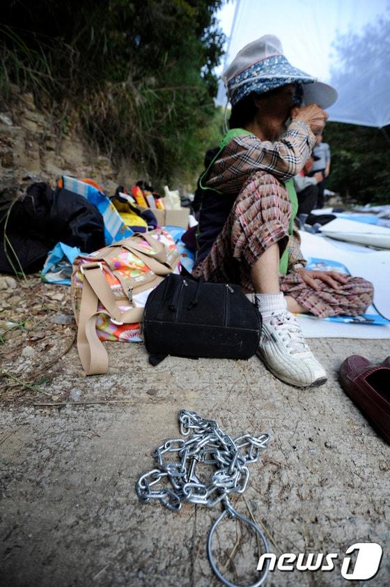 본문 이미지 - 4일 오후 경남 밀양 단장면 89번 공사현장으로 가는 평리입구에서 송전탑 반대 주민 할머니가 몸에 묶은 쇠사슬을 풀고 잠시 쉬고 있다. 2013.10.4/뉴스1 © News1 전혜원 기자
