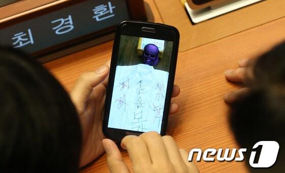 본문 이미지 - 새누리당 하태경 의원이 최경환 원내대표에게 7일 서울 여의도 국회에서 열린 본회의에서 해골 모형과 &#39;끝을보자&#39;라고 적힌 사진을 보여주고 있다. 2013.10.7/뉴스1 © News1   송원영 기자