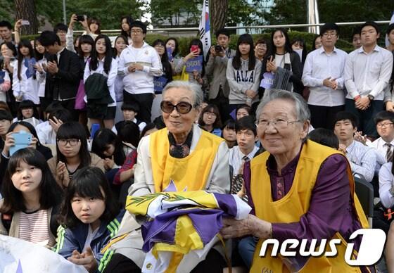 본문 이미지 - 9일 오후 서울 종로구 일본대사관 앞에서 열린 제1095차 일본군 '위안부' 문제 해결을 위한 정기 수요시위에서 김복동·길원옥 할머니가 미국 CMU 호프 교수가 준 평화의 깃발을 받아 들고 있다. 2013.10.9/뉴스1 © News1   안은나 기자