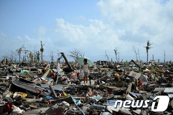 본문 이미지 - 필리핀 국가재난사태....하이옌으로 인해 무너진 필리핀 레이테섬 타클로반의 주택가 집 잔해 사이로 한 여성이 걷고 있다. © AFP=News1   박현우 기자