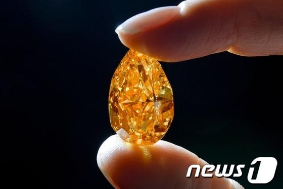 본문 이미지 - 12일(현지시간) 스위스 제네바의 크리스티 경매에서 3150만달러(약 337억8400만원)에 낙찰된 세계 최대 크기의 오렌지색 다이아몬드인 '더 오렌지'의 모습. 더 오렌지의 무게는 14.82캐럿이다.© AFP=News1 