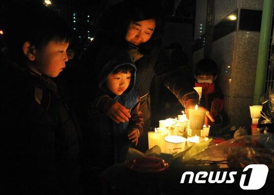 본문 이미지 - 울산에서 계모의 학대로 숨진 A양의 넋을 기리기 위한 촛불추모제가 13일 저녁 A양이 다니던 학교 앞에서 열리고 있다. 추모식에 참석한 아이와 엄마가 촛불을 밝히고 있다. 2013.11.13/뉴스1 © News1   노화정  기자