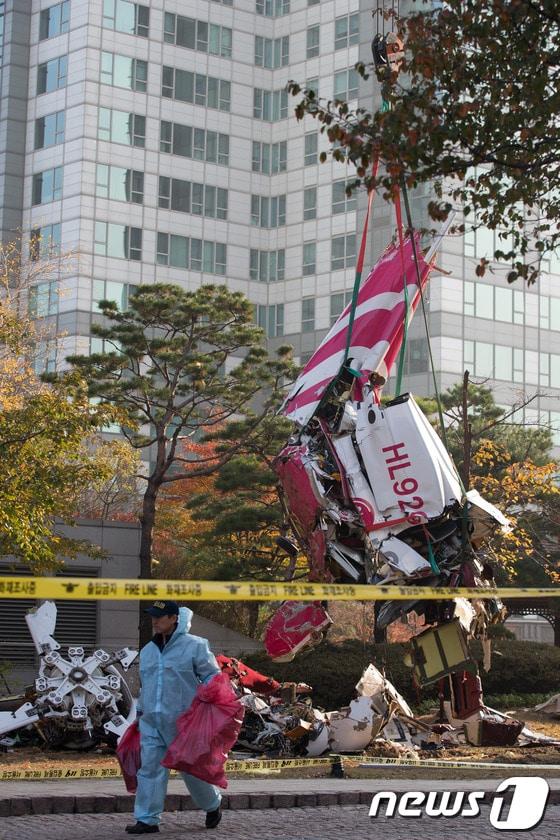 본문 이미지 - 16일 오전 서울 삼성동 아이파크 아파트에 민간 헬리콥터가 충돌해 추락하는 사고가 발생했다. 이날 오후 인부들이 추락한 헬기 잔해를 인양하고 있다.이 사고로 기장 1명과 부기장 1명이 사망한 것으로 알려졌다. 2013.11.16/뉴스1 © News1   유승관 기자