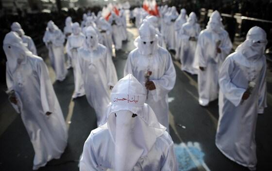 본문 이미지 - p미국의 백인우월단체 KKK단원처럼 머리에서 발끝까지 온통 흰색 복장을 한 바레인의 시아파신자들이 15일&#40;현지시간&#41; 시아파 최대 명절인 아슈라를 맞아 다이에서 열린 의식 동안 꽃을 들고 있다. 아슈라는 이슬람교 창시자 마호메트의 손자로 7세기에 순교한 이맘 후세인을 기리는 날이다. ©AFP=뉴스1 /p