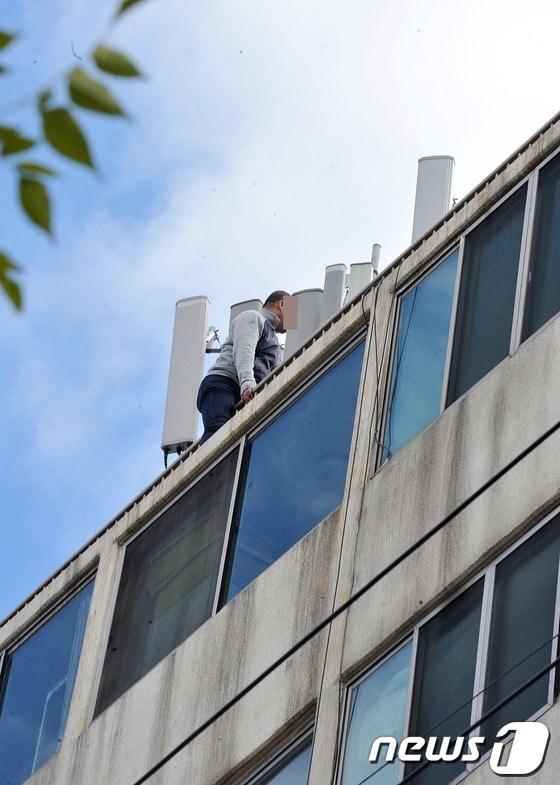 본문 이미지 - 22일 낮 12시20분경 중국인 뤼모&#40;43&#41;씨가 제주시 연동 신광초등학교 인근 7층 짜리 아파트 건물 옥상 난간에 걸터 앉아 출동한 경찰, 119구조대와 대치중이다. 뤼씨는 제주시내 모 카지노에서 도박을 하다 8000만원을 잃자 불만을 품고 이같은 짓을 저지른 것으로 알려졌다. 2013.11.22/뉴스1 © News1   이상민 기자