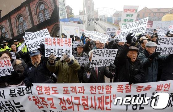 본문 이미지 - 어버이연합 회원들을 비롯한 보수단체 회원들이 24일 오후 서울 중구 명동성당에서 천주교 정의구현사제단을 규탄하는 기자회견을 열고 구호를 외치고 있다. © News1 손형주 기자
