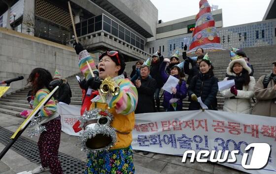 본문 이미지 - 국정원 대선개입은폐 문화예술인탄압저지 공동대책위원회 소속 회원들이 12일 오후 서울 세종문화회관 계단에서 열린 공대위 결성 기념 기자회견에서 국정원 대선개입 은폐하고 문화예술인을 탄압하는 정부를 비판하는 공연을 하고 있다. 2013.12.12/뉴스1 © News1   박지혜 기자