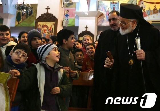 본문 이미지 - 다마스쿠스의 한 교회에서 시리아 말룰라 난민을 위해 예배를 집도한 그레고리오스 3세 라함 동방정교 대주교와 난민 어린이들의 모습.© AFP=News1 