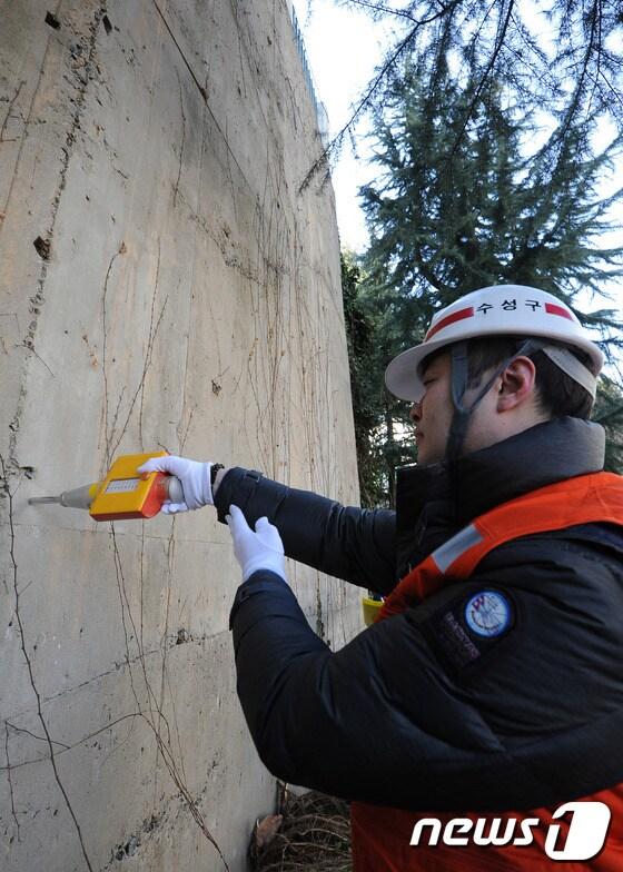 본문 이미지 - 해빙기를 맞아 대구 수성구 생활 안전과 직원들이 건축물의 안전사고를 예방하기 위해 21일 오전 대구 수성구 한 아파트 옹벽을 슈미트 해머를 이용해 콘크리트의 강도를 측정하고 있다. 2013.02.21/뉴스1 © News1 김영진 기자