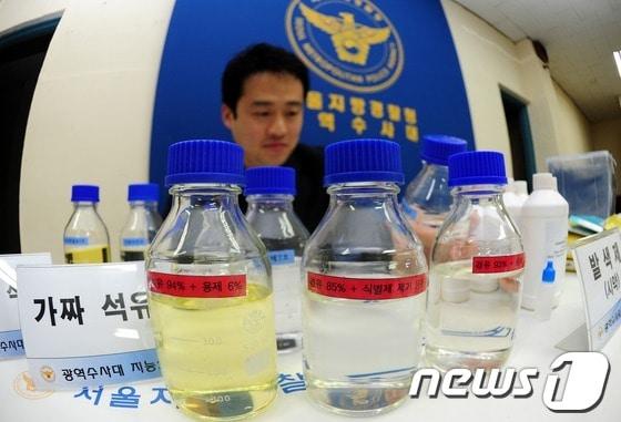 본문 이미지 - 서울지방경찰청 광역수사대가 전국 각지에 주유소를 차려놓고 가짜 휘발유, 경유 등을 만들어 판매한 혐의&#40;석유 및 대체연료 사업법 위반·사기&#41;로 주유소 대표업자 조모씨를 구속했다고 밝힌 28일 서울 마포 광역수사대에서 담당 수사관이 압수된 가짜 석유를 설명하고 있다. 경찰에 따르면 조씨는 서울, 경기, 충북 등지에 본인 명의로 4개, 동생 조씨 명의로 2개, 지인 A씨 명의로 5개 등 총 11개 주유소를 차려놓고 2010년 1월부터 지난 2월까지 가짜휘발유 등 1230만ℓ를 제조·판매해 200억원 상당을 편취한 혐의를 받고 있다. 2013.2.28/뉴스1 © News1   한재호 기자