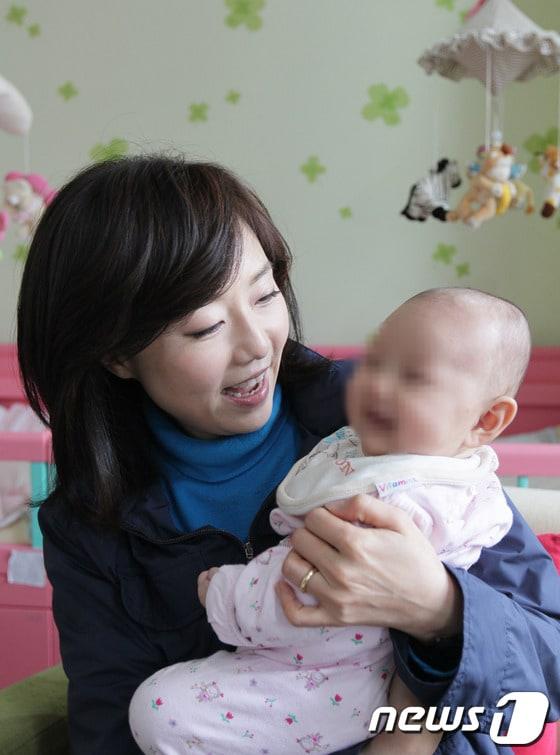 본문 이미지 - 조윤선 여성가족부 장관이 미혼모자가족 복지시설에서 아기를 안고 있다. (여성가족부 제공) /뉴스1 © News1 김보영 