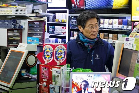 본문 이미지 - 김능환 전 중앙선거관리위원장이 서울 동작구 상도동에 위치한 아내가 운영하는 편의점에서 계산대를 보고 있다./뉴스1 © News1 유승관 기자