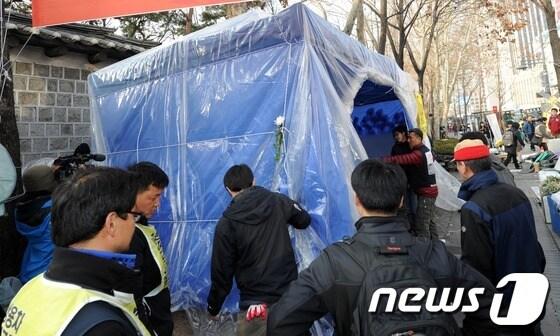 본문 이미지 - 쌍용자동차 해고노동자들이 지난 3월 문화재청이 덕수궁 담장을 보수공사하는데 지장이 없도록 천막을 옮기고 있다./뉴스1 © News1 손형주 기자