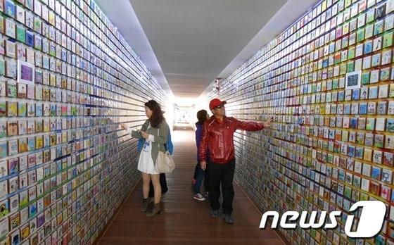 본문 이미지 - 꿈의 다리는 주 박람회장과 국제습지센터를 연결하는 '물위의 전시관'이다. 길이 175ｍ, 폭 7.29m로 다리 위에 컨테이너 30개를 연결하고 다리 외벽을 오색글자로 장식해 알록달록 색동옷을 입은 듯 꾸몄다. 이 다리는 2010년 중국 상하이엑스포 때 한국관을 설계한 강익중 작가가 꾸민 것이다. 꿈의 다리 내부 벽면은 세계 각국 어린이 14만 5000명의 꿈이 적힌 작은 타일을 부착했다. 가로 세로 7.62㎝인 나무 타일에는 꿈이 담긴 예쁜 그림들이 새겨져 있다. © News1 서순규 기자